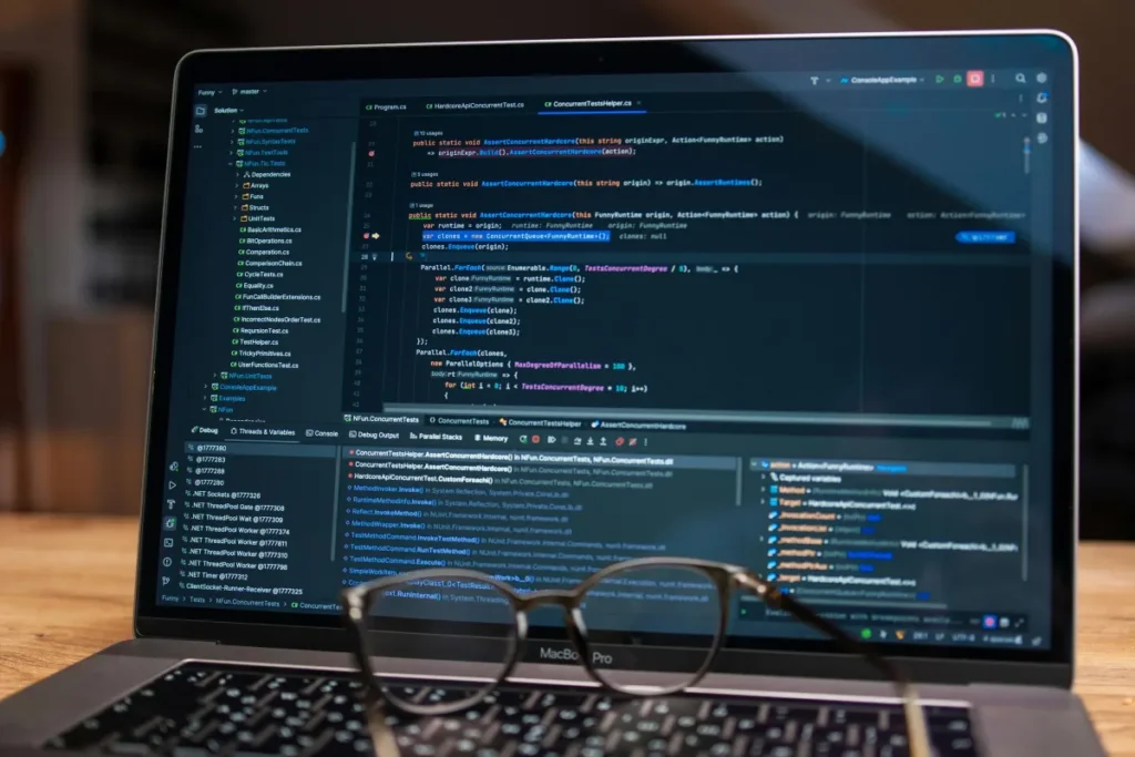 Layar laptop menampilkan kode program dan alat debugging sebagai bagian dari proses software testing